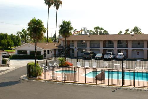 a pool in front of a hotel with palm trees at Colony Inn in Buena Park