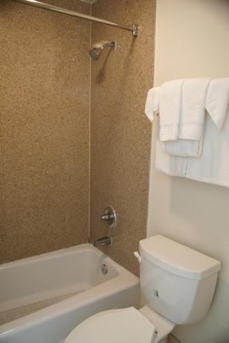 a bathroom with a toilet and a shower with towels at Colony Inn in Buena Park