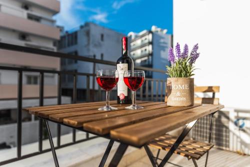 een houten tafel met twee glazen wijn op een balkon bij TownHall Apartment's in Rhodos-stad