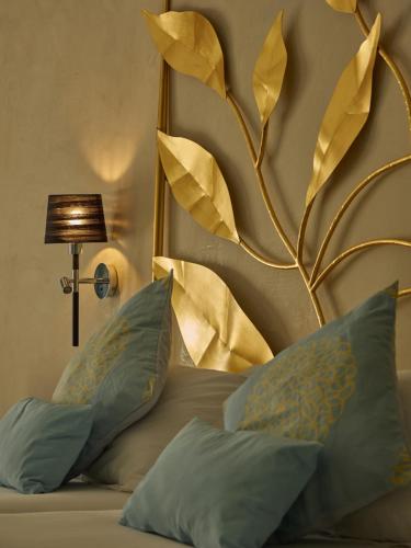 a bedroom with a bed with a gold headboard and pillows at Hotel Petit Cala Fornells in Paguera