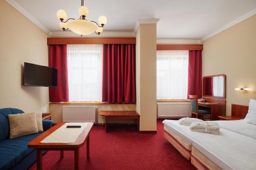 ein Hotelzimmer mit einem Bett und einem Sofa in der Unterkunft Wellness Hotel Lužan in Rumburk