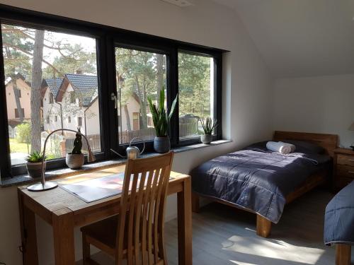 a bedroom with a bed and a desk and a table and window at Dom Jan in Pobierowo