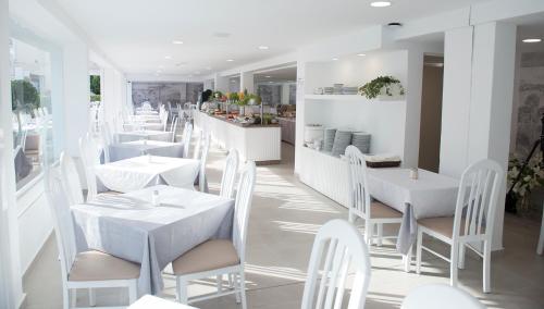 a white restaurant with white tables and chairs at Hotel Chevy & Suites in Cala Ratjada