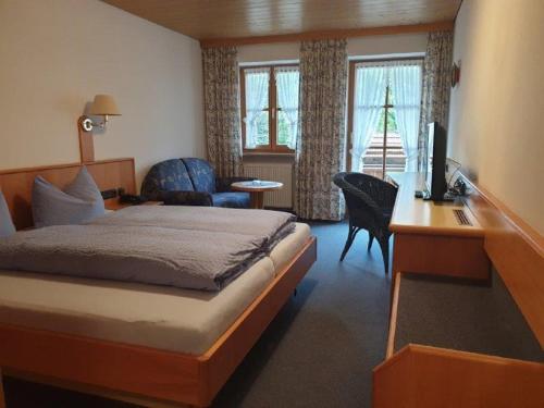 a bedroom with a bed and a desk with a television at Landhaus Beim Joaser in Schwangau