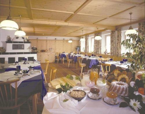 Cette grande chambre comprend des tables et des chaises avec de la nourriture. dans l'établissement Landhaus Beim Joaser, à Schwangau