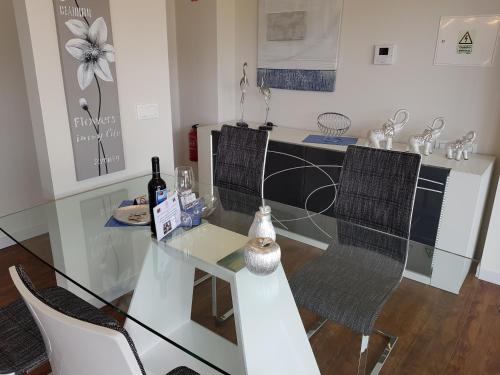 a glass table with two chairs and a counter with wine bottles at Madalenas Palace - Sunrise in Funchal