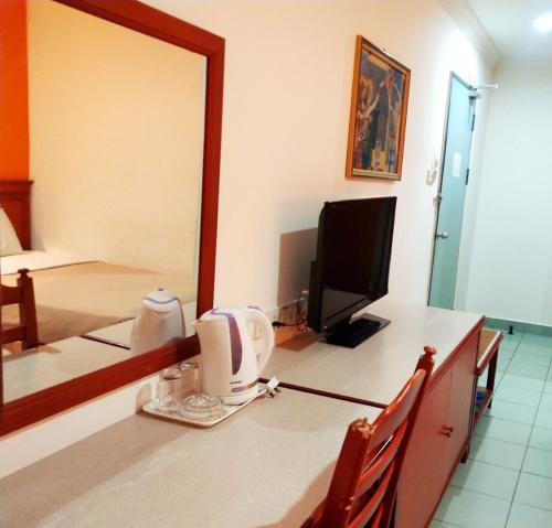 a bathroom with a vanity with a mirror and a tv at Megah Inn in Kota Kinabalu