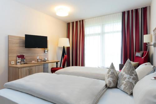 a hotel room with two beds and a flat screen tv at Hotel St. Georg in Bad Aibling