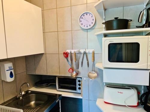 a small kitchen with a microwave and a sink at Aux Studios du Parc in Plombières-les-Bains