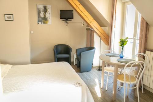 a room with a bed and a table and chairs at Aux Studios du Parc in Plombières-les-Bains