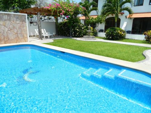 a large blue swimming pool in front of a house at Hotel Pez Vela in Manzanillo