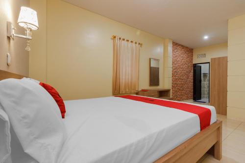 a bedroom with a large white bed in a room at RedDoorz Plus near Pantai Malalayang Manado in Manado