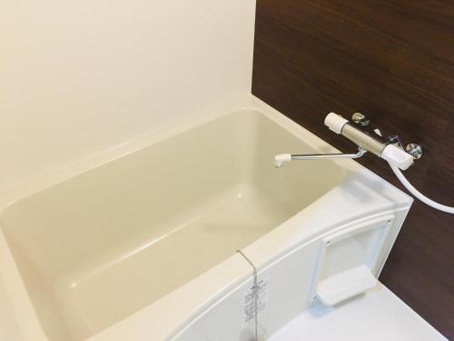 a white bath tub with a faucet in a bathroom at Thanyaporn Hotel in Takayama