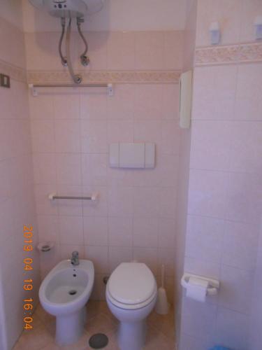 a white bathroom with a toilet and a sink at PENSIONE VERDE LUNA in Orbetello