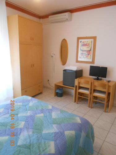 a bedroom with a bed and a desk with a television at PENSIONE VERDE LUNA in Orbetello