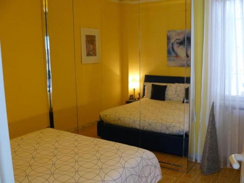 a yellow room with two beds and a mirror at Un gioiello con vista mare in Moneglia