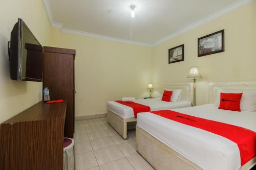 a hotel room with two beds and a flat screen tv at RedDoorz @ Malalayang 2 Manado in Manado