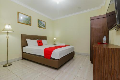 a bedroom with a bed with a red blanket at RedDoorz @ Malalayang 2 Manado in Manado