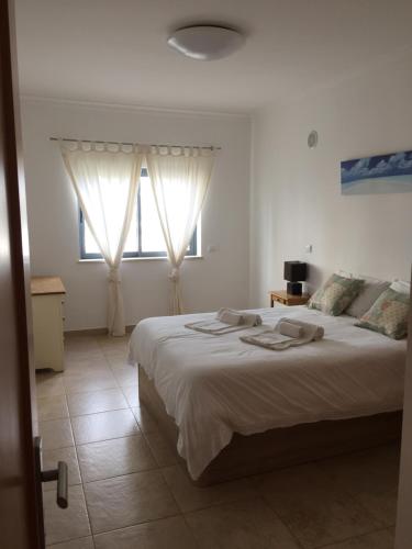 a bedroom with a large bed with two windows at Quinta das Palmeiras in Lagos