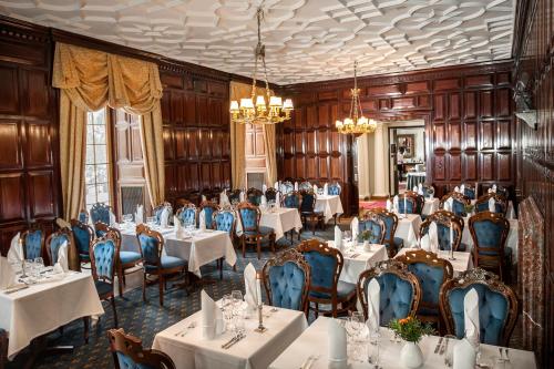 a dining room with tables and chairs and chandeliers at Hotel Vanajanlinna in Hämeenlinna