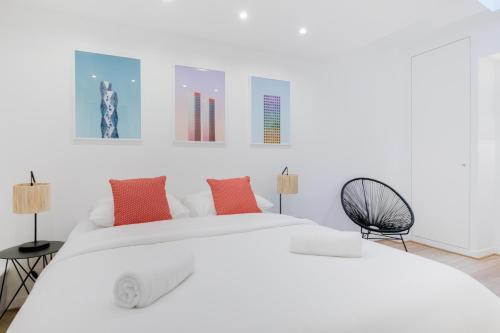 a white bedroom with a large white bed with orange pillows at Loft Design for 8 people in Heart of Paris in Paris