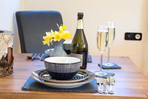 una mesa con una botella de vino y un jarrón con flores amarillas en Serenity Lodge en Llandeilo