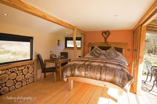 a bedroom with a bed and a desk and a window at Serenity Lodge in Llandeilo