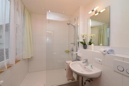 a white bathroom with a sink and a shower at Gästehaus Maxheim in Oberstdorf