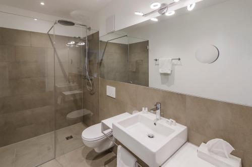 a bathroom with a sink and a shower and a toilet at Hotel Daneu in Nüziders