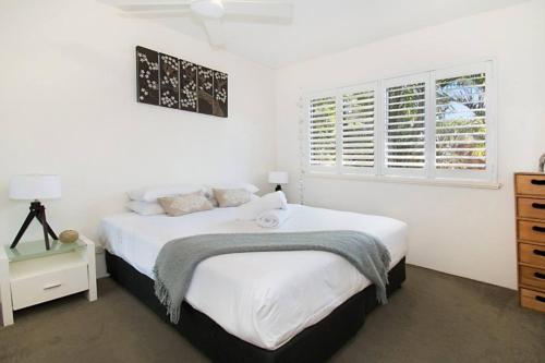 a white bedroom with a bed and a window at Indiah in Byron Bay