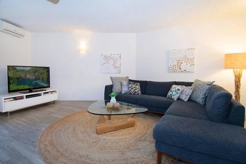 a living room with a blue couch and a tv at Indiah in Byron Bay