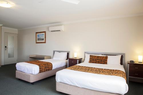 a hotel room with two beds and two lamps at Mandarin Motel in Macksville