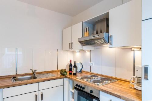 een keuken met witte kasten en een wastafel bij Gästehaus Neteler in Bad Zwischenahn