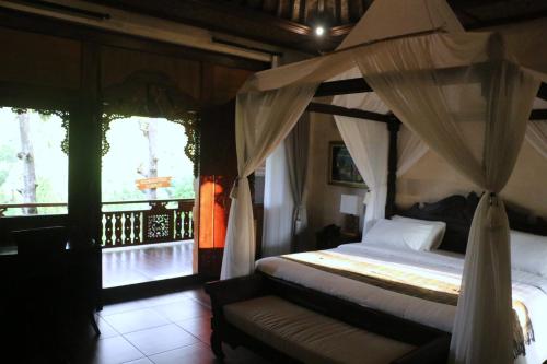 a bedroom with a canopy bed with a couch and windows at Shanti Natural Panorama View Hotel in Singaraja