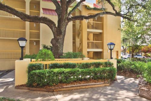 ein Gebäude mit einer Hecke vor einem Gebäude mit einem Baum in der Unterkunft La Quinta by Wyndham Charleston Riverview in Charleston