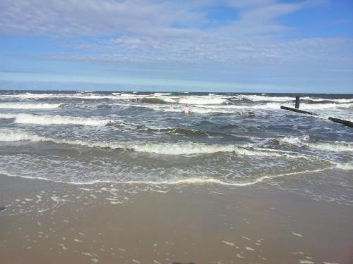 a beach with waves and a pier in the ocean at Strandburg, das smarte Penthouse in ÜckeRitz mit PKW Stellplatz! in Ueckeritz