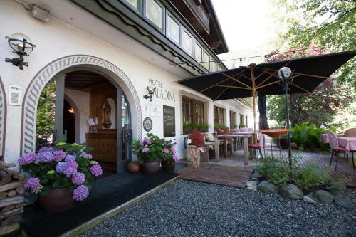 un patio esterno con ombrellone, tavoli e sedie di Bio-Hotel Saladina a Gaschurn