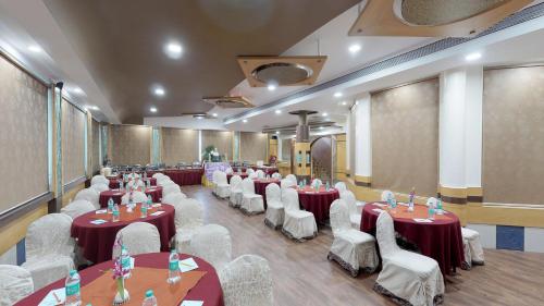 a banquet hall with tables and white chairs at Pai Viceroy in Bangalore