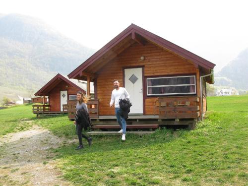 un homme et une femme debout devant une petite maison dans l'établissement Sæbø Camping, à Eidfjord