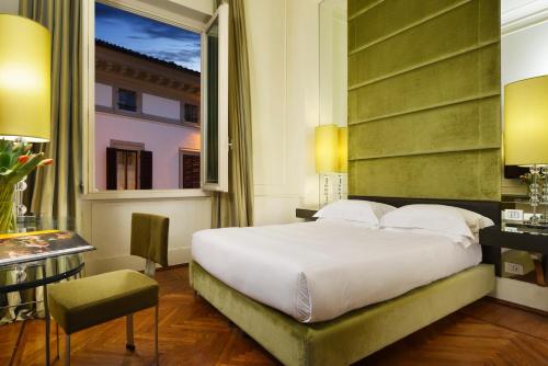 a bedroom with a bed and a desk and a window at Brunelleschi Hotel in Florence