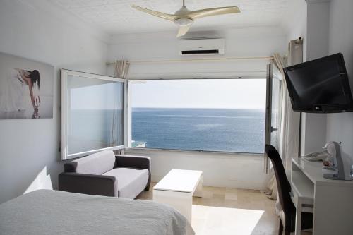 a bedroom with a bed and a window with the ocean at Hotel Boutique Milla de Plata in Torreguadiaro