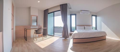 Schlafzimmer mit einem Bett und einem Schreibtisch mit einem Balkon in der Unterkunft Am2tree in Chanthaburi