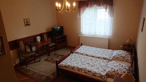 a bedroom with a bed and a table and a television at Apartamenty i Pokoje Willa Dafne in Ciechocinek
