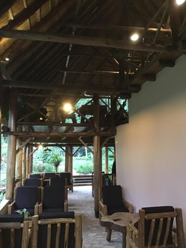 a row of chairs in a room with wooden ceilings at Kibale Forest Camp by NATURE LODGES LTD in Kyenjojo