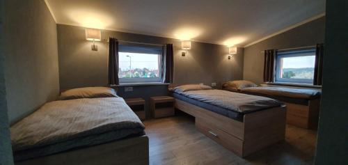 a room with three beds and two windows at Budziechów Noclegi in Lubsko