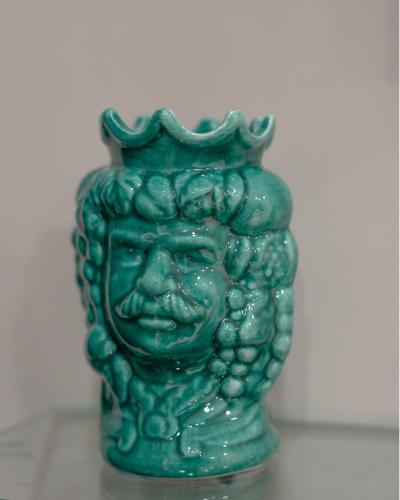 a green vase with a face in a crown at Marranzanu Rooms in Santa Teresa di Riva