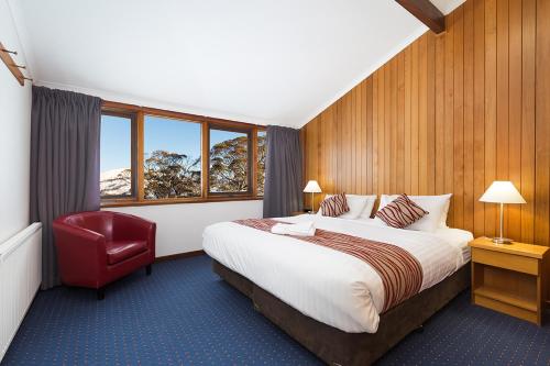 une chambre d'hôtel avec un lit et un fauteuil rouge dans l'établissement Valhalla Perisher, à Perisher Valley