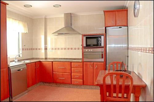 La cuisine est équipée de placards rouges et d'un réfrigérateur en acier inoxydable. dans l'établissement Dalí al Mar, à Conil de la Frontera
