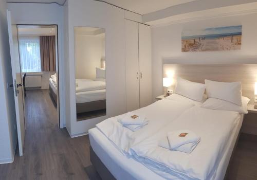 a bedroom with a large white bed and a mirror at Hotel Angelo in Saarbrücken