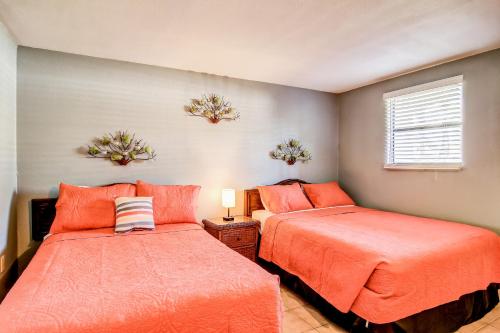 two beds in a bedroom with orange sheets at Sand & Surf Sea Mist Condos in Port Aransas